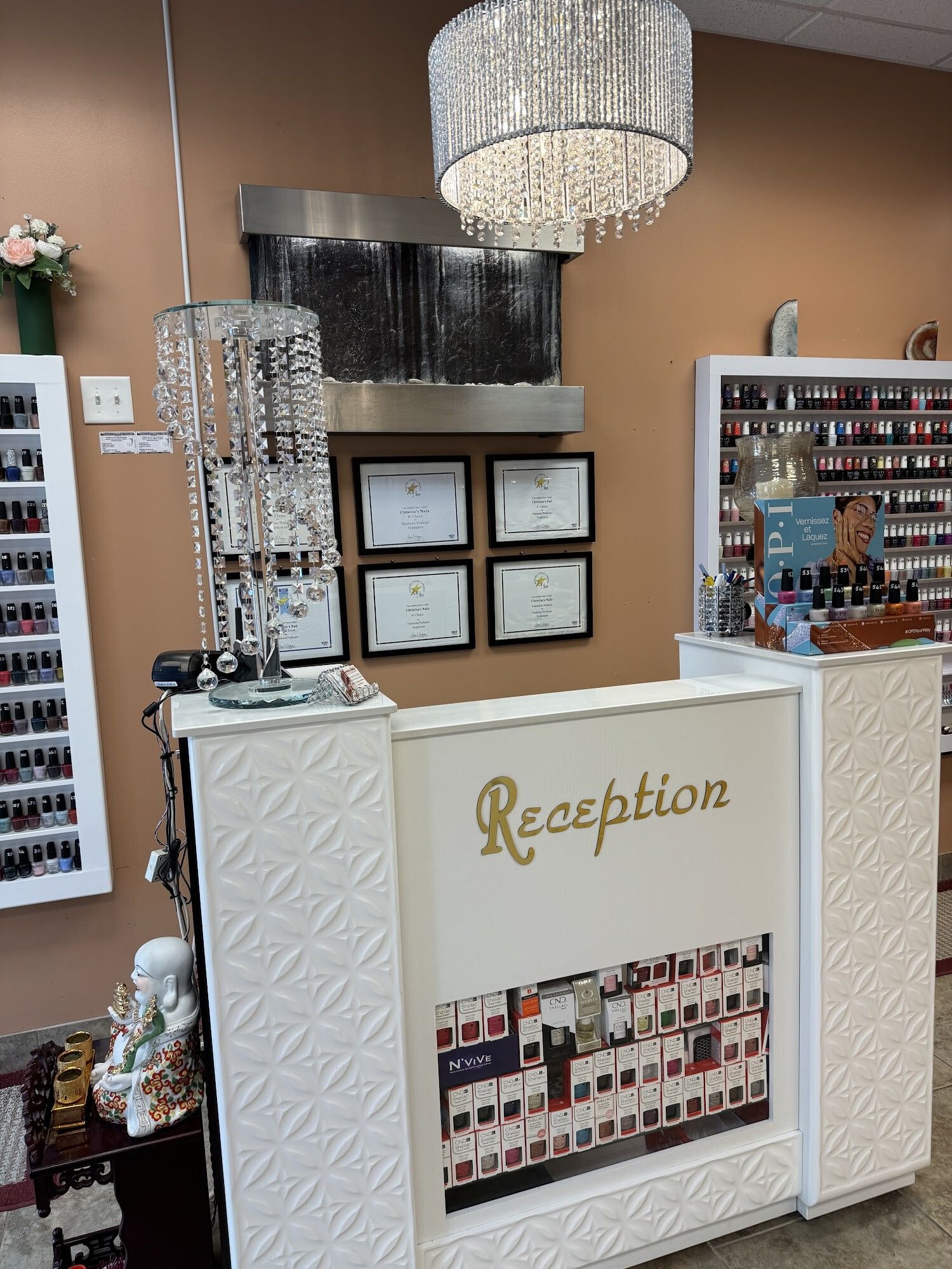 White reception desk with crystal chandelier at Christine’s Nails